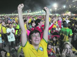 Mientras en el primer plano un aficionado brasileño celebra, detrás de él un par de colombianos aceptan la derrota de su equipo. AFP /