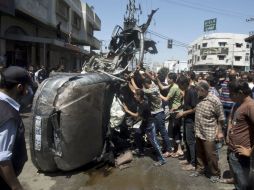 Personas manipulan un vehículo afectado durante un ataque aéreo israelí en la ciudad de Gaza. AFP /