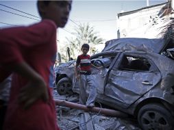 Un par de jóvenes palestinos observan un vehículo destruido por un ataque aéreo israelí. AFP /