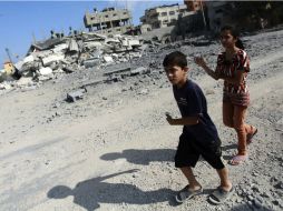 Dos niños palestinos caminan entre escombros de una casa destruida en un bombardeo israelí sobre el campo de refugiados de Al Nuseirat. EFE /