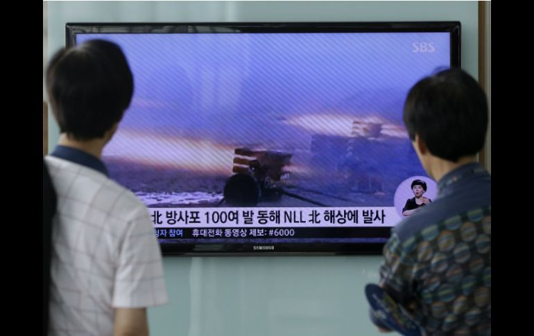 Dos hombres en Seúl observan en una televisión el nuevo operativo que usa artillería norcoreana. AP /
