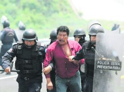 TRIFULCA. Policías preventivos detienen a un manifestante tras el enfrentamiento del 9 de julio en San Bernardino Chalchihuapan. SUN /