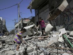 Un par de niñas palestinas recolectan algunas pertenencias luego de un ataque aéreo israelí a un edificio en Gaza. AP /
