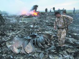 ESCOMBROS. Personal de servicios de seguridad observan los restos del Boeing 777 de Malaysia Airlines. AP /