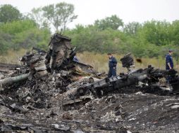 Rescatistas caminan por los restos del MH17, cuyo vuelo de 298 personas a bordo fue derribado por un presunto misil ucraniano. AFP /
