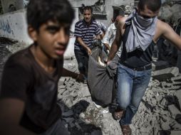 Palestinos recuperan el cuerpo de un hombre entre los escombros de lo que fue su casa, luego de un ataque israelí. AFP /