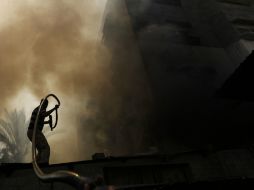 Un palestino trata de sofocar el fuego de un edificio en llamas. AFP /