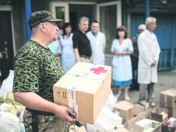 Suministros. Un activista ucraniano del batallón Donbass reparte ayuda humanitaria en una escuela en la localidad de Popasnaya. EFE /