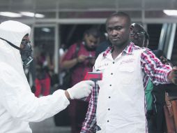 Un funcionario de salud nigeriano utiliza un termómetro en un trabajador de la terminal de un aeropuerto de Nigeria. AP /