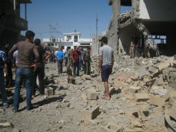 Iraquíes inspeccionan el lugar donde hubo un doble atentado con coches bomba. AP /