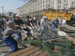 Trabajadores y voluntarios recolectan cacharros que formaban parte de las barricadas en la calle principal de la capital de Ucrania. EFE /