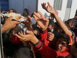 Iraquíes desplazados reciben comida en un campamento en Siria. ARCHIVO /