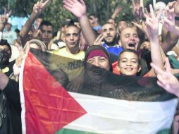 Jerusalén. Palestinos agitan una bandera nacional como signo de la victoria tras la tregua permanente entre Israel y Hamas. AFP /