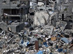 Hombres palestinos caminan sobre los escombros de sus casas destruidas en el barrio Tufah en el este de la ciudad de Gaza. AFP /