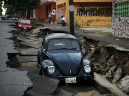 Un par de automóviles permanecen sobre una calle colapsada luego de una fuerte lluvia en Veracruz ocasionada por ''Dolly''. AP /