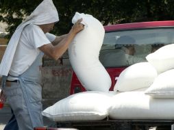 Un hombre coloca costales de azúcar en una camioneta. ARCHIVO /