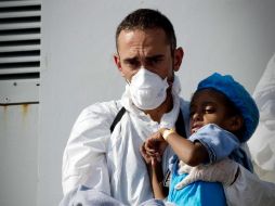Un trabajador de la Cruz Roja ayuda a un menor que llegó al puerto de Nápoles, Italia. EFE C. Fusco  /