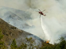 Un helicóptero lanza una carga de agua en el Cañon de Silverado. AP  S. Gangwer  /