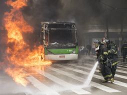 Bomberos apagan un autobús incendiado por manifestantes hoy durante disturbios Sao Paulo. EFE  A. Cadena  /