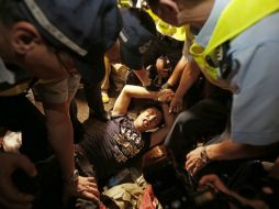 La Policía organiza una cadena humana para contener a los ciudadanos enfurecidos contra los jóvenes, pero son derribados. AP / W. Santana
