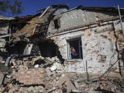 Una mujer mira por una ventana en una vivienda destruída por proyectiles de artillería en la localidad de Peski, cerca de Donetsk. EFE / K. Grishin