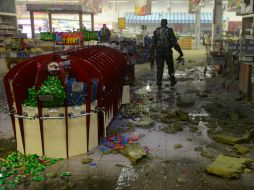 Un separatista prorruso recoge pedazos del misil que cayó en el supermercado. AFP / J. Macdougall