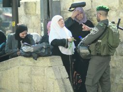 RECLAMO. Mujeres palestinas hablan con un policía israelí tras el cierre de la mezquita de Al-Aqsa. AP /