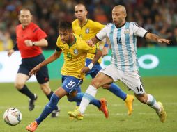 El jugador brasileño Neymar (i) se disputa el balón con el argentino Javier Mascherano (d). EFE / H. H. Young