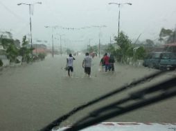 Habitantes de La Marquella caminan por una calle inundada debido a las fuertes lluvias que dejó a su paso 'Trudy'. EFE / F. Meza