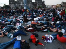 Personas acostadas en el suelo, cubriéndose la cara con fotografías de los jóvenes desaparecidos, en protesta por los hechos ocurridos. EFE / S. Gutiérrez