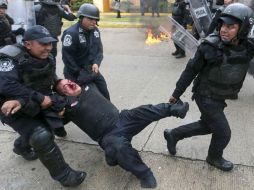 Polocías cargan a un compañero herido. AFP / P. Pardo