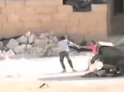 El 'pequeño héroe' rescata a una niña jalándola de la mano y llevándola detrás de un muro. YOUTUBE / ShaamNetwork S.N.N