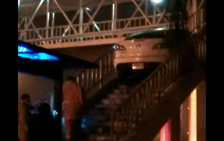 El vehículo, un Mazda blanco, quedó sobre las escaleras del puente; según autoridades, el conductor escapó de la escena. ESPECIAL /
