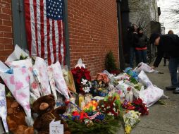 Personas dejan ofrendas y flores en el lugar donde los dos policías fueron asesinados. AFP / D. Emmert