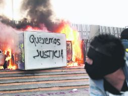 Hartazgo social. Un encapuchado arroja una bomba molotov al Congreso de Guerrero. AFP /