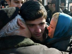 El chico es abrazado por sus padres al pasar por las puertas del centro de detención. AP /