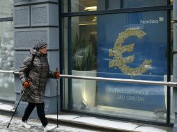 Una mujer pasa al lado de un anuncio con la leyenda: ''El euro llegará pronto a Lituania''. AP / M. Kulbis