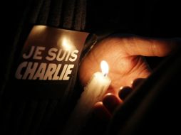 Un hombre sostiene una vela y un cártel con un mensaje que dice ''Yo soy Charlie'', durante una manifestación en París. AP / C. Ena