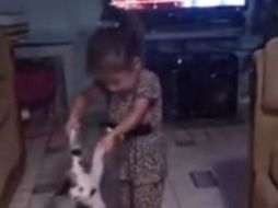 La niña juega con el gato obedeciendo la voz de una mujer. YOUTUBE /