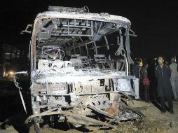 Oficiales paquistaníes inspeccionan restos del autobús que ardió en llamas tras el impacto con la pipa que transportaba petróleo. EFE / S. Akber