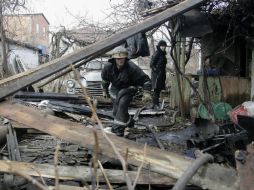 Un bombero inspecciona los restos de una vivienda, en presencia de su dueña (d), tras un bombardeo. EFE / A. Ermochenko