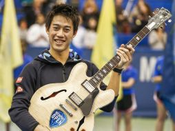 Kei Nishikori sostiene la presea obtenida durante el Abierto de Memphis, una guitarra Gibson. EFE / T. Maury