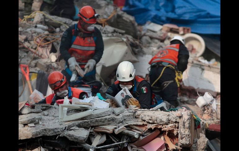 Varios rescatistas revisan objetos encontrados en la búsqueda de más sobrevivientes en los condominios de Tlalpan.