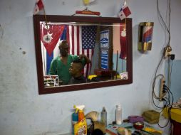 La Habana. Un cliente en una peluquería ambientada con banderas de Estados Unidos y Cuba. AP / R. Espinosa