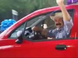 En la grabación se le observa conduciendo un auto rojo con un moño azul en el cofre y desde el cual saluda a quien hace la filmación. FACEBOOK / Hilario Ramírez Villanueva