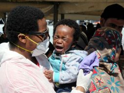Un rescatista sostienen a un pequeño niño llorando mientras su madre desembarca en el bote de la Marina. AP / A. Sapone