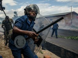 Un oficial de policía sostiene una macana al tiempo que militares se defienden de los protestantes. AFP / J. Huxta