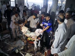 Varias personas recogen algunos de los escombros generados por el atentado. EFE / STR