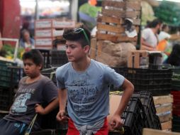 Jóvenes ayudan a los clientes hasta con cuatro cajas, en el Mercado de Abastos. EL INFORMADOR / A. Hinojosa