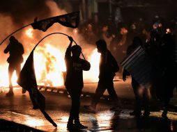 Estudiantes permanecen junto a una barricada de fuego durante una protesta contra la reforma de la educación en Santiago. AFP / M. Bernetti
